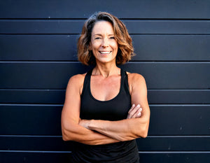 Midlife woman standing with her arms folded across her chest smiling Old Lady Gains Blog regarding women challenging the outdated ideas about “acting your age”