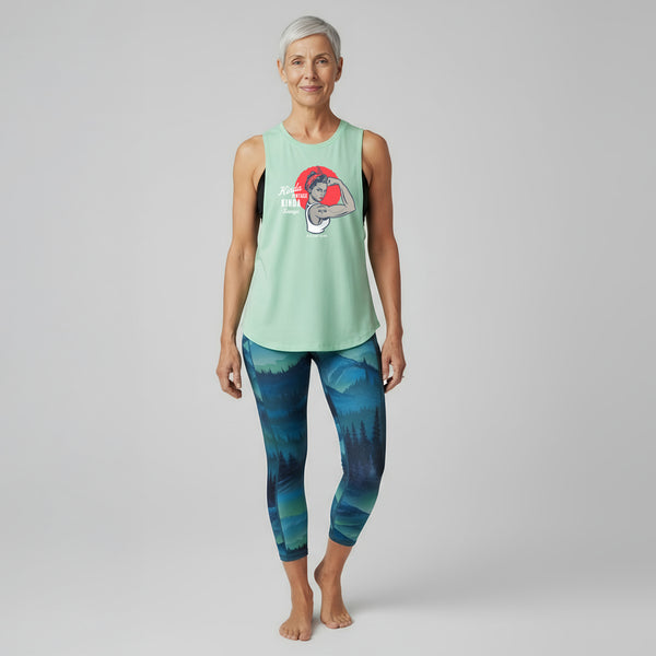 Woman wearing a mint-green muscle tank with a retro Rosie-style graphic that reads Kinda Vintage Kinda Savage.