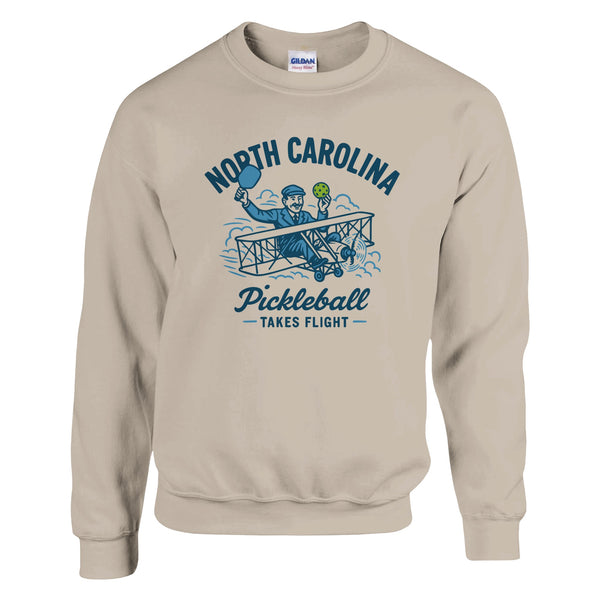 Pickleball sweatshirt featuring Orville Wright's first flight holding a pickleball with the text “North Carolina Pickleball Takes Flight”.