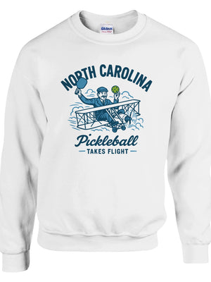Pickleball sweatshirt featuring Orville Wright's first flight holding a pickleball with the text “North Carolina Pickleball Takes Flight”.