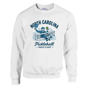 Pickleball sweatshirt featuring Orville Wright's first flight holding a pickleball with the text “North Carolina Pickleball Takes Flight”.