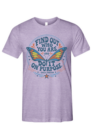 A heather purple short-sleeve t-shirt with a colorful graphic on the front featuring a butterfly and the text 'FIND OUT WHO YOU ARE AND DO IT ON PURPOSE' by Dolly Parton.