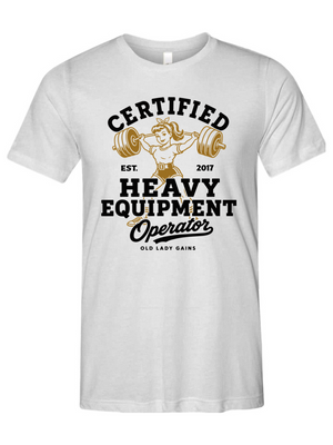A white short-sleeve crewneck t-shirt featuring a vintage-style graphic on the front with the text 'CERTIFIED HEAVY EQUIPMENT Operator' and an illustration of a woman lifting a barbell.