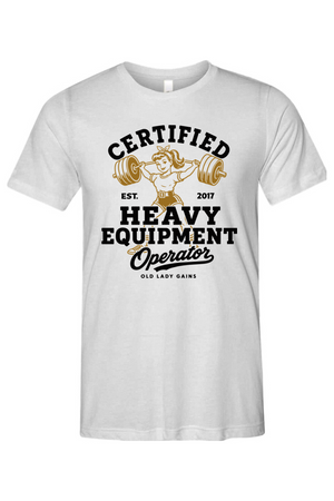A white short-sleeve crewneck t-shirt featuring a vintage-style graphic on the front with the text 'CERTIFIED HEAVY EQUIPMENT Operator' and an illustration of a woman lifting a barbell.