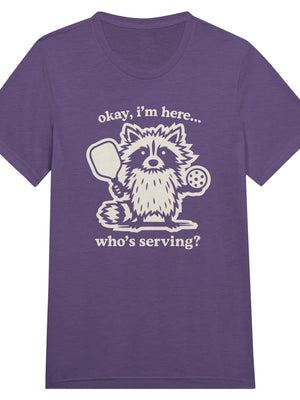 Funny pickleball graphic featuring a raccoon holding a paddle and pickleball with the text “Okay, I’m Here… Who’s Serving?”