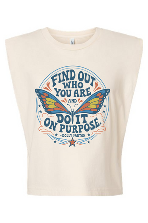 An off-white sleeveless crop top featuring a colorful graphic print of a butterfly inside a circular frame with the text 'FIND OUT WHO YOU ARE AND DO IT ON PURPOSE - DOLLY PARTON'.