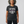 A woman with curly gray hair wearing a dark heather gray graphic t-shirt that reads 'LIFTING IS MY FAVORITE SPORT' in white and purple text, paired with black leggings, against a light gray studio background.