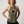 Middle-aged Woman wearing a green tank top with a logo and text that reads REMEMBER ONLY YOU CAN AGE STRONG on a plain background