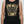 Person wearing a black tank top with gold graphic and text on a white background
