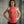 Woman wearing a red workout tank top with empowering text in front of a concrete wall.
