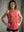 Woman wearing a red workout tank top with empowering text in front of a concrete wall.