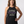A smiling woman wearing a dark charcoal heather halter tank top with the text 'STRONG WOMEN RAISE Standards' printed on the front, posed against a light gray studio background.