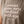 A close-up of a sleeveless taupe-brown tank top featuring a light pink printed quote that reads 'women grow more radical with age -gloria steinem'.