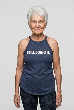 Older athletic woman wearing “Still Doing It” halter tank top for women over 40 fitness apparel