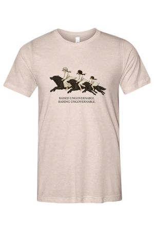 A light beige crewneck t-shirt featuring a vintage-style graphic of three women riding horses, with the text 'RAISED UNGOVERNABLE. RAISING UNGOVERNABLE.