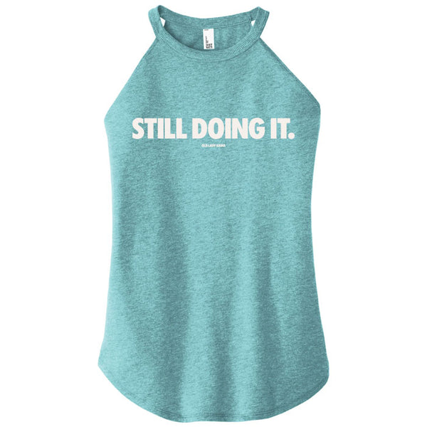 Teal tank top with 'STILL DOING IT.' text on a white background