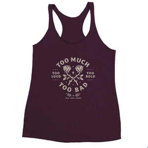 Strong middle-aged woman flexing in a racerback tank that reads Too Loud Too Bold Too Much Too Bad.