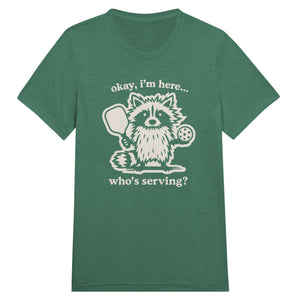 Funny pickleball graphic featuring a raccoon holding a paddle and pickleball with the text “Okay, I’m Here… Who’s Serving?”