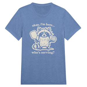 Funny pickleball graphic featuring a raccoon holding a paddle and pickleball with the text “Okay, I’m Here… Who’s Serving?”