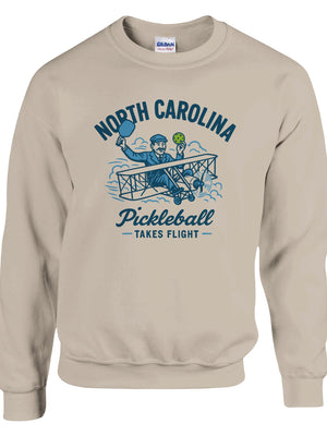 Pickleball sweatshirt featuring Orville Wright's first flight holding a pickleball with the text “North Carolina Pickleball Takes Flight”.