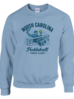 Pickleball sweatshirt featuring Orville Wright's first flight holding a pickleball with the text “North Carolina Pickleball Takes Flight”.