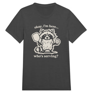 Funny pickleball graphic featuring a raccoon holding a paddle and pickleball with the text “Okay, I’m Here… Who’s Serving?”