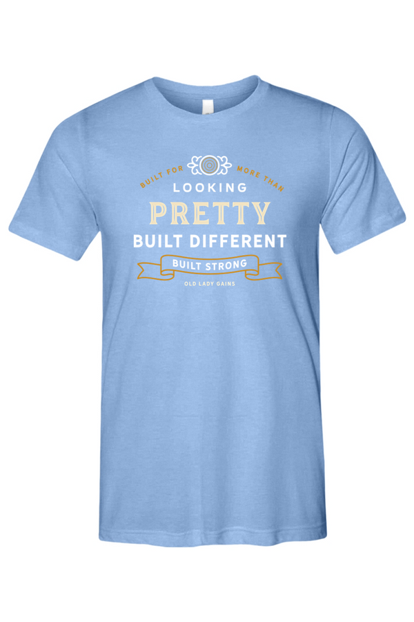 Woman's light blue t-shirt reading "Built for More Than Looking Pretty. Built Different. Built Strong." by Old Lady Gains, motivational fitness apparel for women over 40.