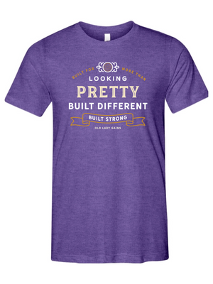 Woman's purple t-shirt reading "Built for More Than Looking Pretty. Built Different. Built Strong." by Old Lady Gains, motivational fitness apparel for women over 40.