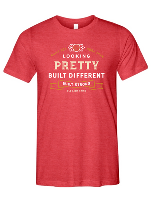 Woman's red t-shirt reading "Built for More Than Looking Pretty. Built Different. Built Strong." by Old Lady Gains, motivational fitness apparel for women over 40.