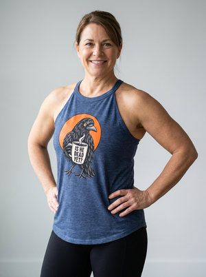 A smiling woman wearing a heathered blue racerback tank top with a graphic of a raven in front of an orange circle and the text 'IS HE DEAD YET?' on the front, paired with black leggings, standing against a light gray studio background.